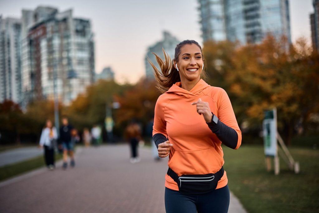 Woman in orange hoodie going for a run to empower herself after a breakup.