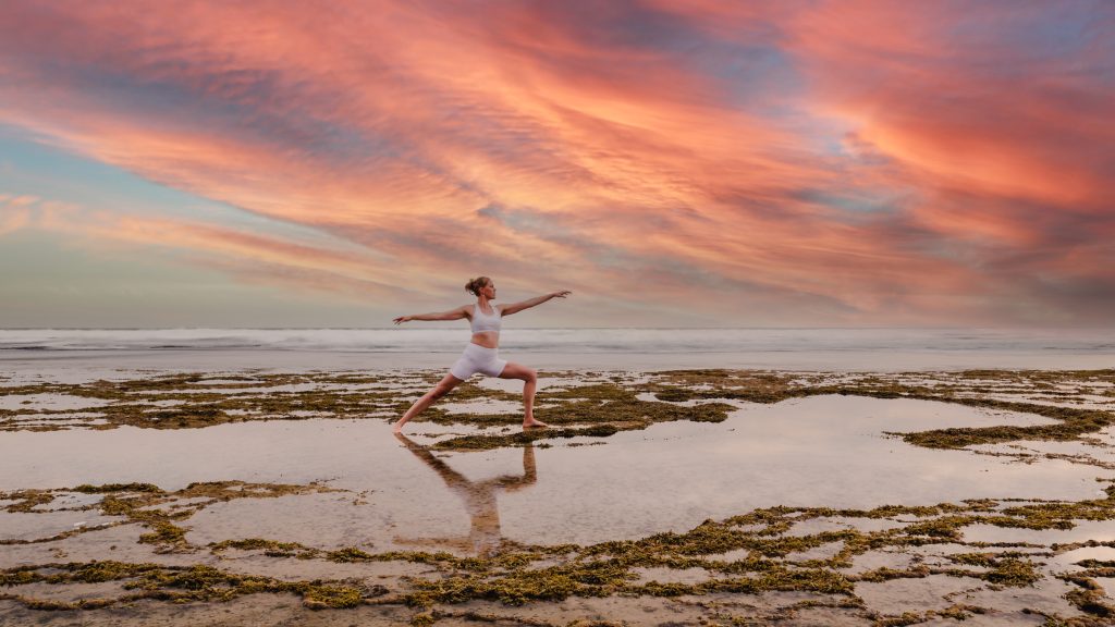 Health mentor doing yoga pose on beach