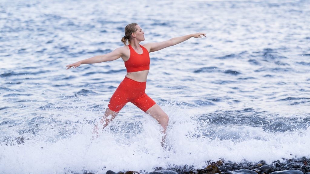 Woman doing Yoga pose in front of ocean.