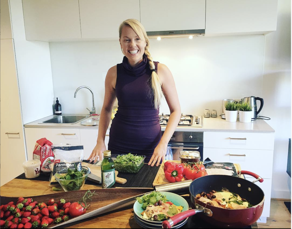 Lifestyle coach and nutritionist standing in kitchen next to healthy foods.