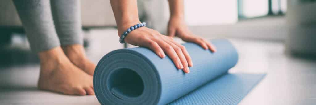 Woman rolling up pilates mat.