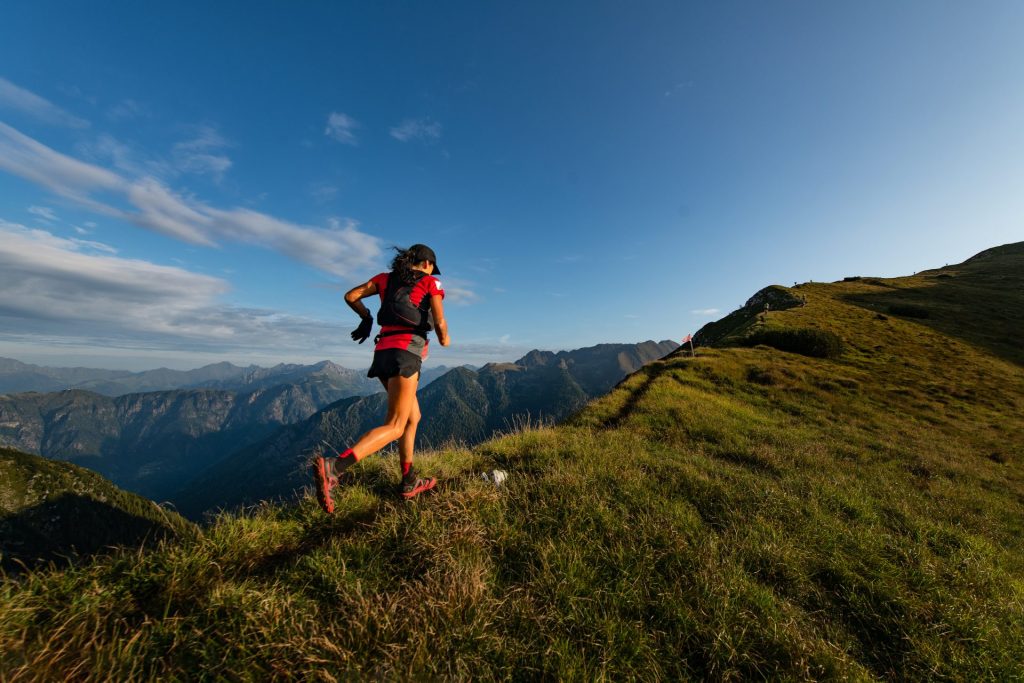 Motivated woman jogging up a tall mountain.