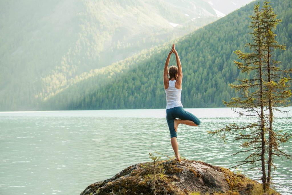 Woman doing yoga pose in front of ocean.