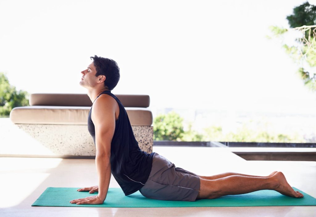 Man practicing his cobra pose on yoga mat.